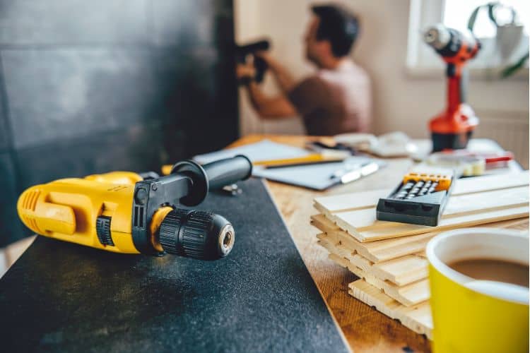 Tools on a Table and a Man Renovating a Wall in the Background